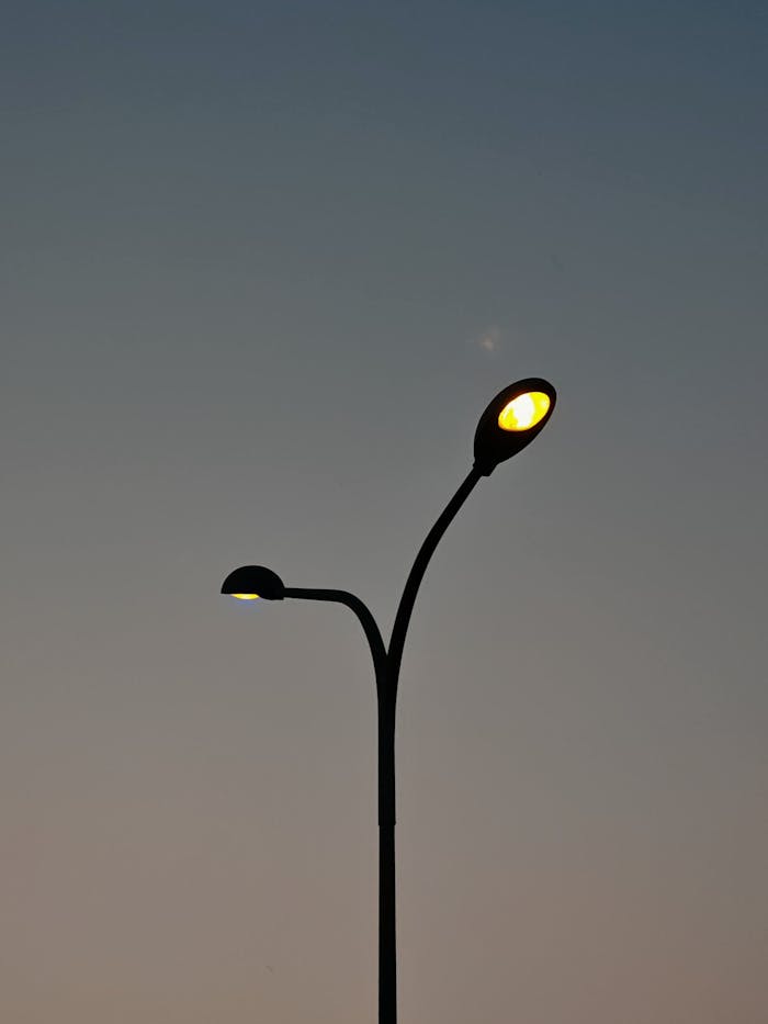 Street lamps against a clear dusk sky, casting a warm glow as night approaches.