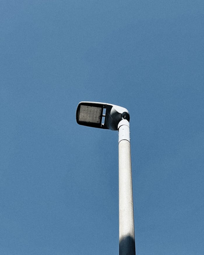 A modern street light stands tall against the clear blue sky, emphasizing urban minimalism.